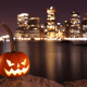 Lit jack-o'-lantern overlooking the New York City skyline at night.