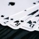 Close-up of playing cards fanned out on a dark wood surface.
