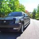 Black Cadillac Escalade limousine parked on a tree-lined street in New Jersey.