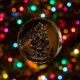 Christmas tree reflected in a glass ornament, surrounded by festive lights.