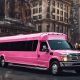 Pink party bus on city street. Perfect for Valentine's Day celebrations. Book your BergenLimo party bus today!
