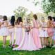 Bride and bridesmaids in pink dresses, posing outdoors for a bridal shower.