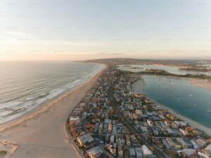 Aerial view of a coastal town with beach and boats, perfect for a bachelorette party.