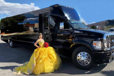 Young woman in yellow quinceañera dress poses by a black party bus. NJ Quinceañera transportation.