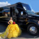 Young woman in yellow quinceañera dress poses by a black party bus. NJ Quinceañera transportation.