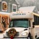 Luxury charter bus decorated for the holidays, parked in front of a snow-covered home. "Charter Bus" is visible on the vehicle.